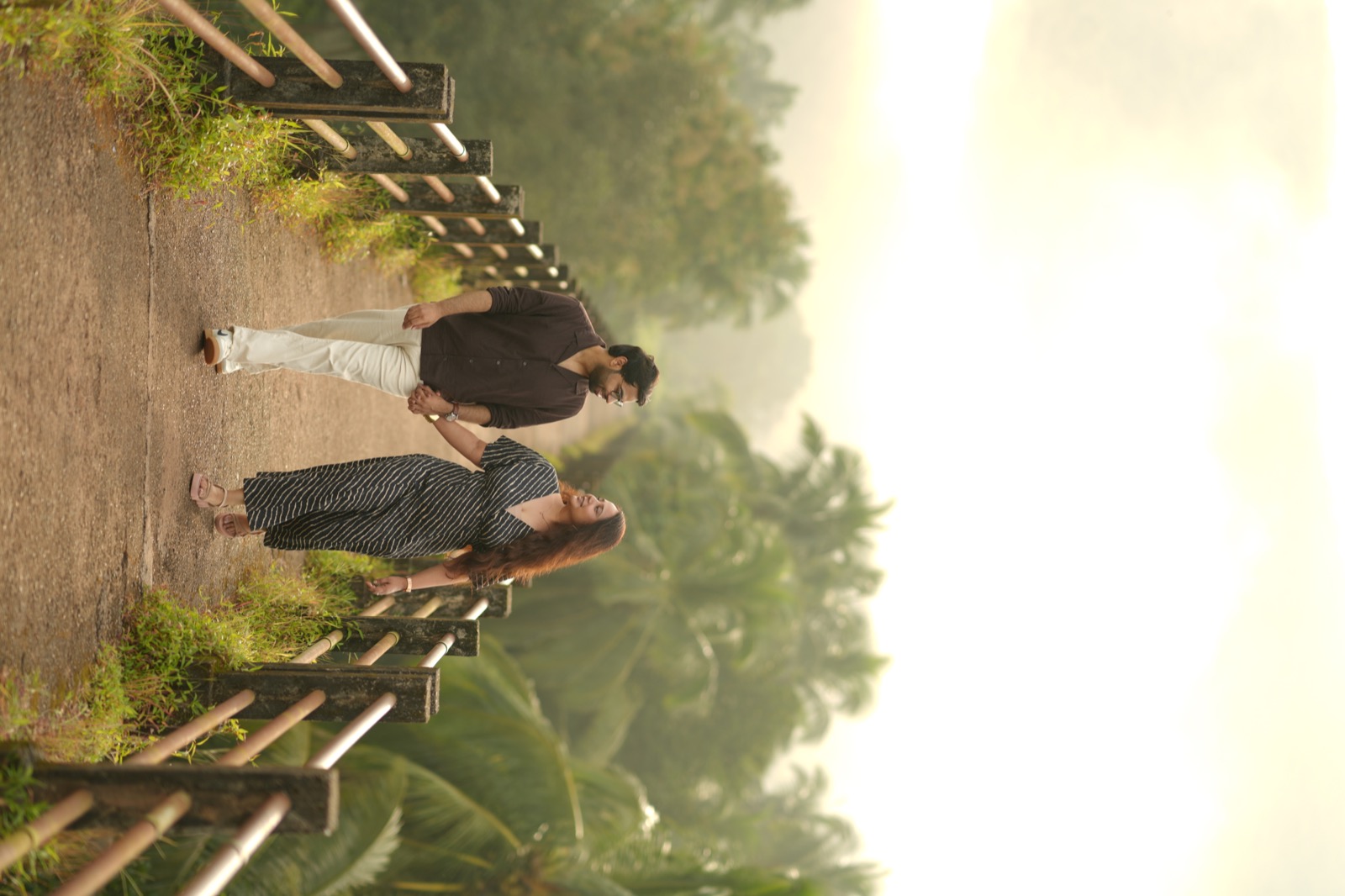 Prateek and Ranu walking hand-in-hand on a rustic bridge