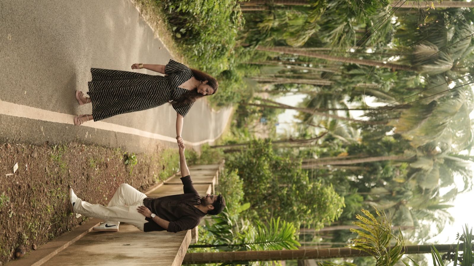 Prateek and Ranu holding hands on a palm-lined path